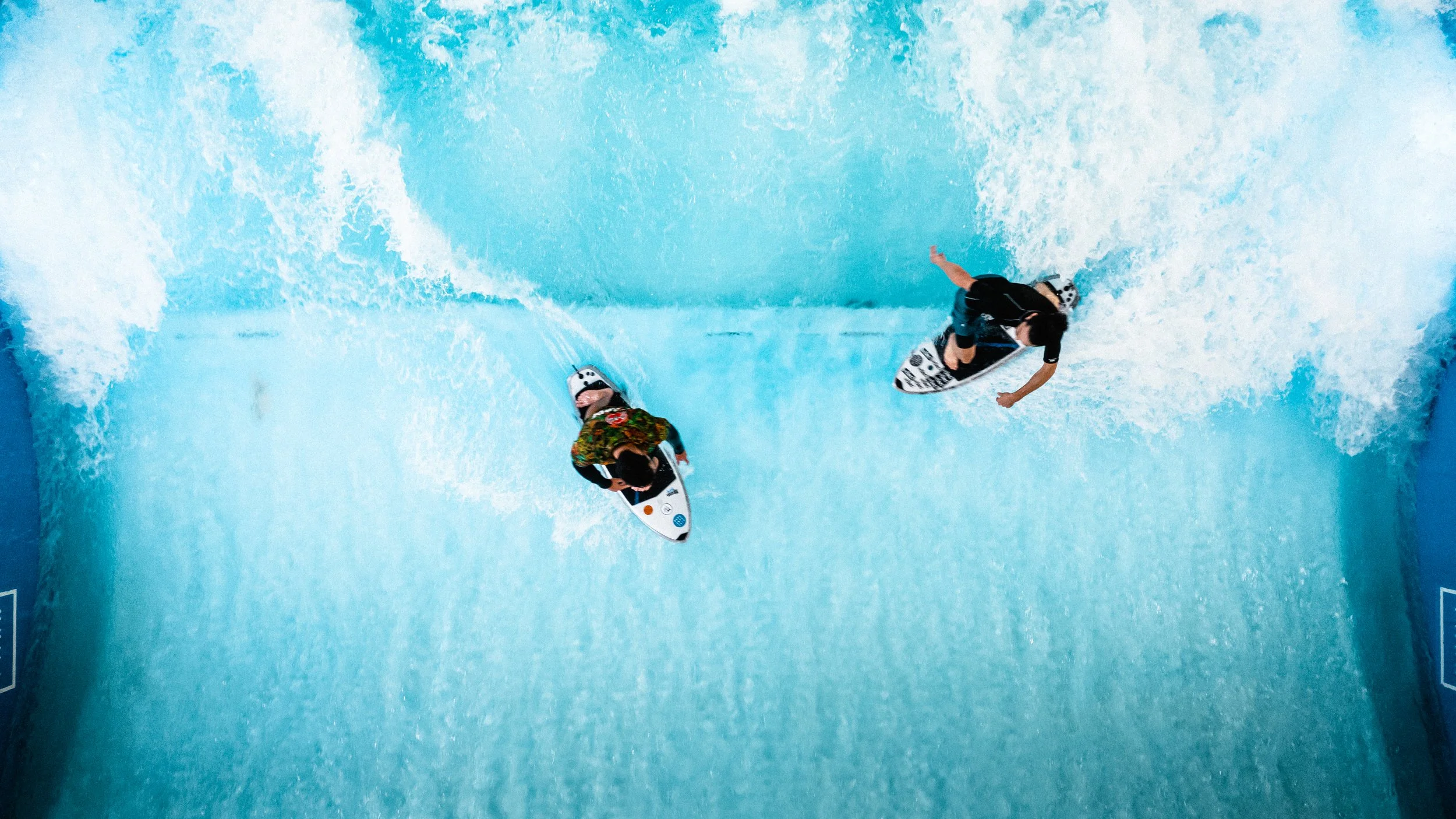 Deux personnes font du surf sur une vague dans une piscine artificielle.